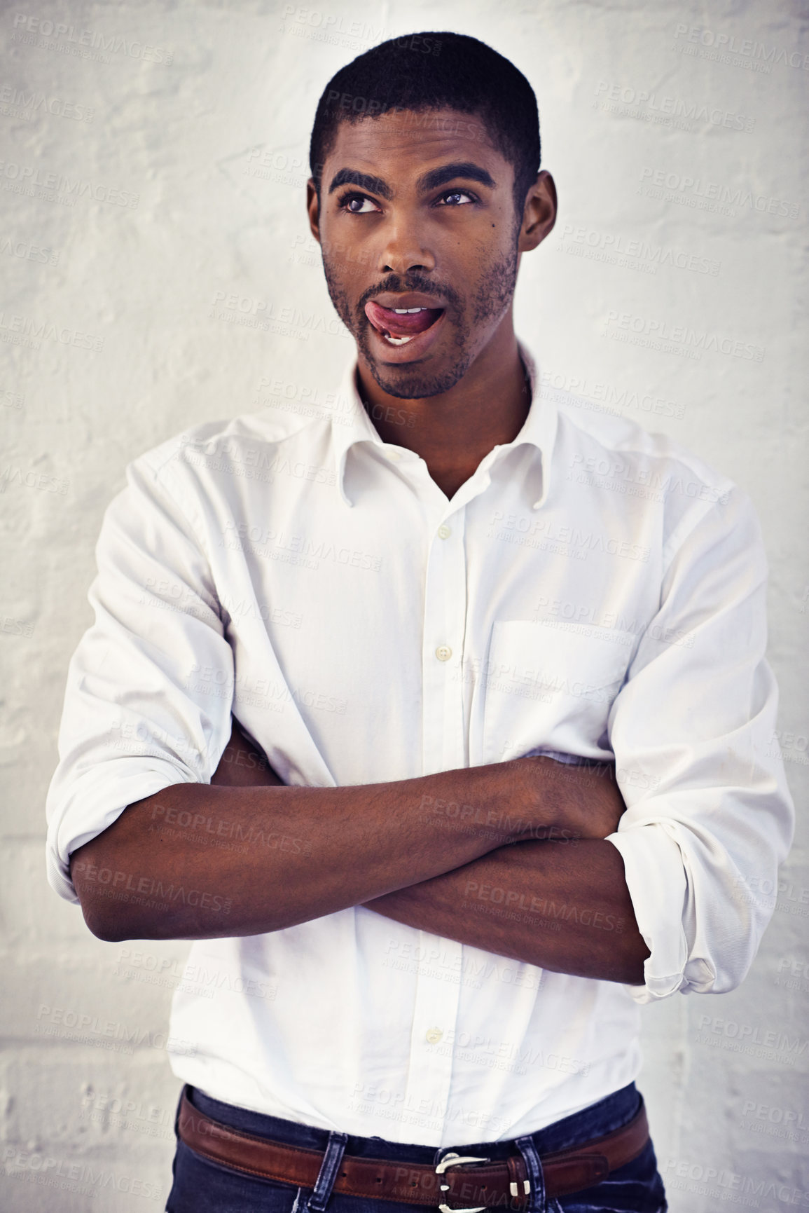 Buy stock photo Shot of a young man with his arms crossed sticking out his tongue
