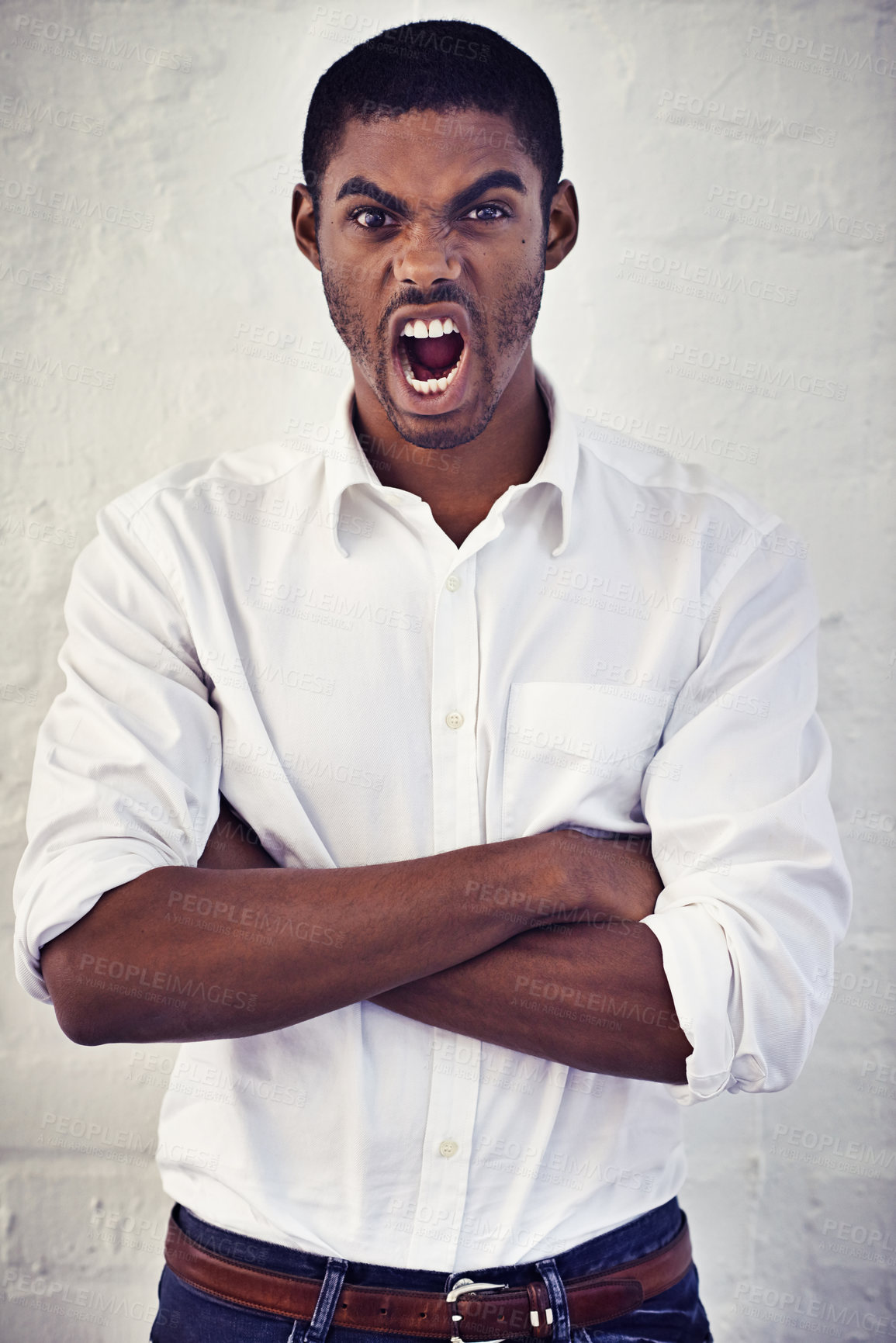 Buy stock photo Portrait of a young man standing with his arms crossed screaming