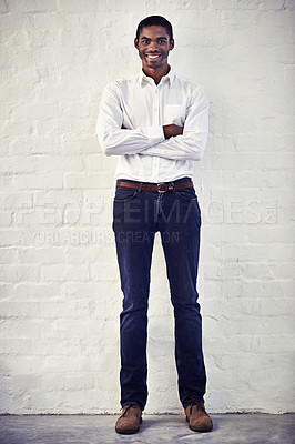 Buy stock photo Shot of a casually dressed young man standing against a brick wall