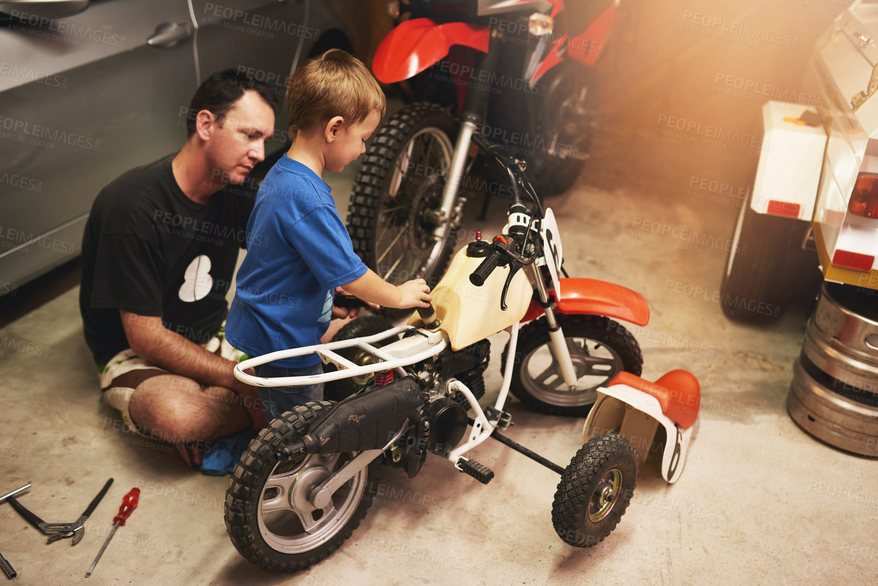 Buy stock photo Parent, child and fixing bike in garage at home for teamwork, support and repair with tools. Family man, father and son for bonding, helping and together as mechanic for motorbike in carport