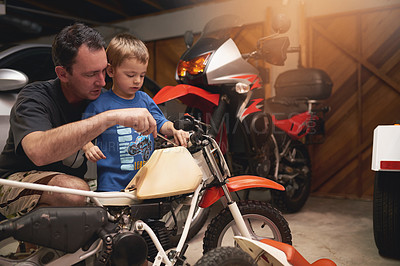 Buy stock photo Parent, son and fixing with bike in garage at home for teamwork, support and repair with tools. Family, father and child for bonding, helping and together as mechanic for motorbike in carport