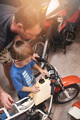 Buy stock photo Dad, child and fixing with bike in garage at home for teamwork, support and repair with tools to educate. Family, father and son for bonding, helping and together as mechanic for motorbike in carport
