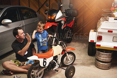 Buy stock photo Shot of a father and son fixing a bike in a garage