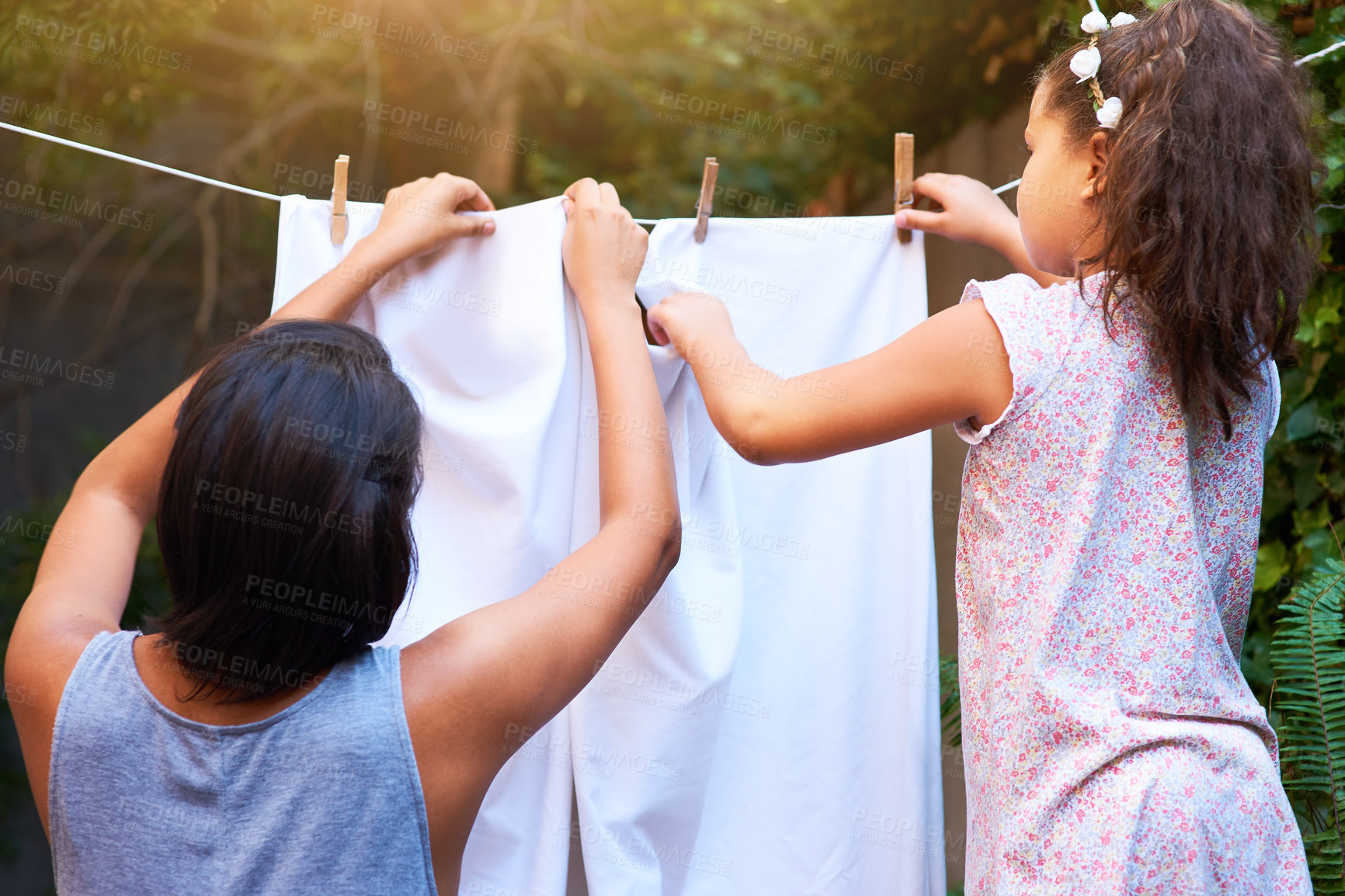 Buy stock photo Teamwork, hanging laundry and a mother and child doing housework, chores and busy with clothes. Cleaning, family and back of a little girl helping mom with clothing on the line in backyard together