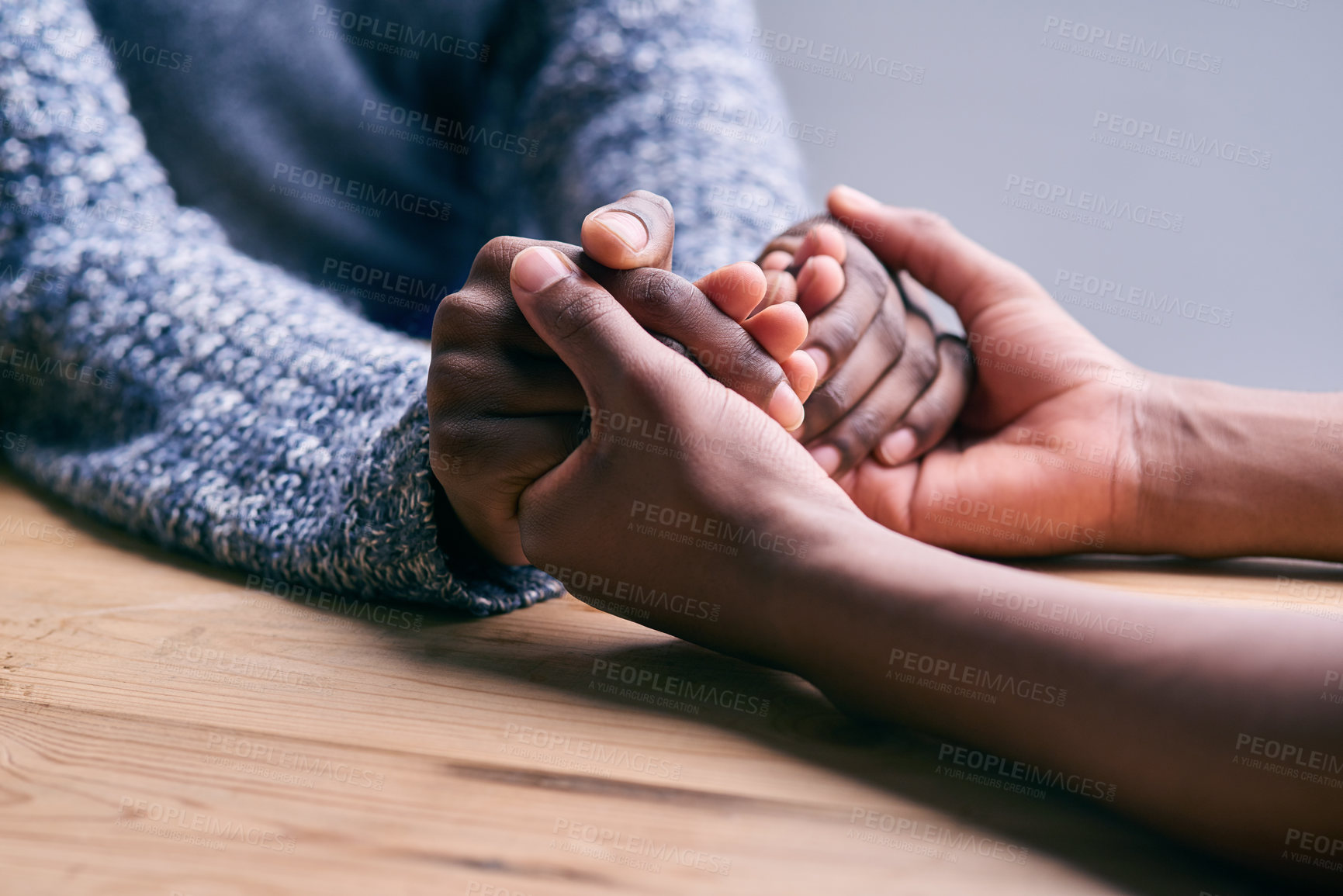 Buy stock photo Love, support and people holding hands for unity, compassion and sympathy by a wood table. Empathy, care and couple or friends with affection in an intimate bonding moment together for grief and loss
