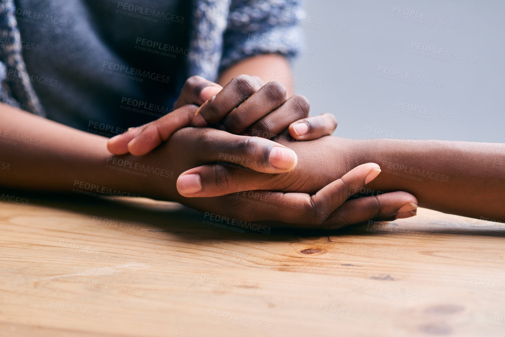 Buy stock photo Cropped shot of a two people holding hands in comfort on a table