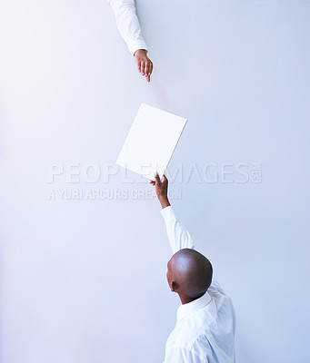 Buy stock photo Rearview shot of a young businessman handing a document to a colleague in an office