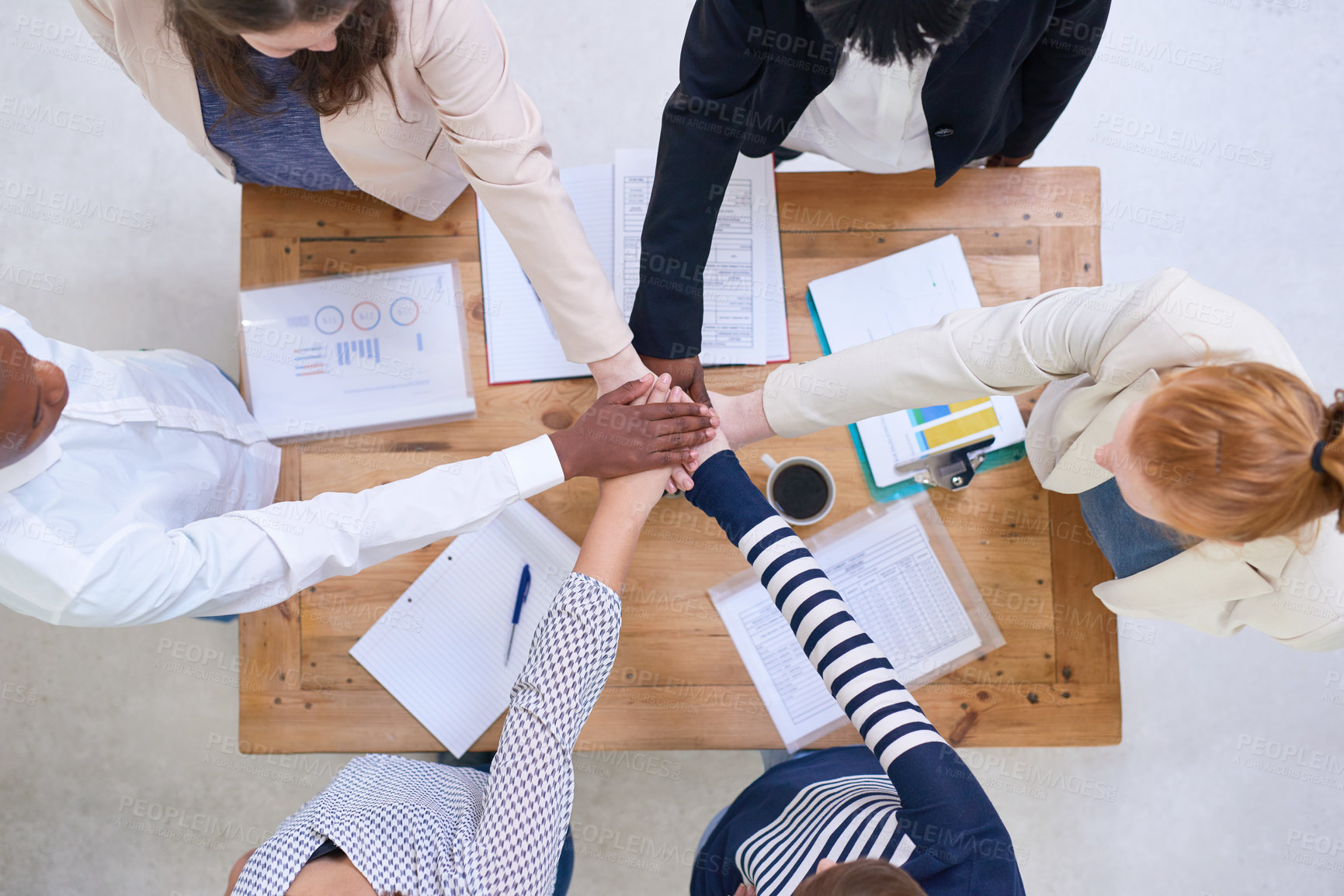 Buy stock photo High angle shot of a group of colleagues standing around a desk with their hands in a huddle