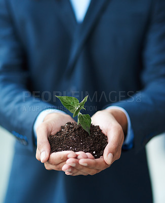 Buy stock photo Cropped shot of a businessman holding a plant growing in soil