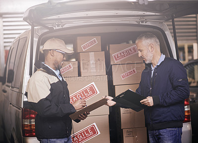 Buy stock photo Shot of two delivery men having a discussion next to a van filled with boxes