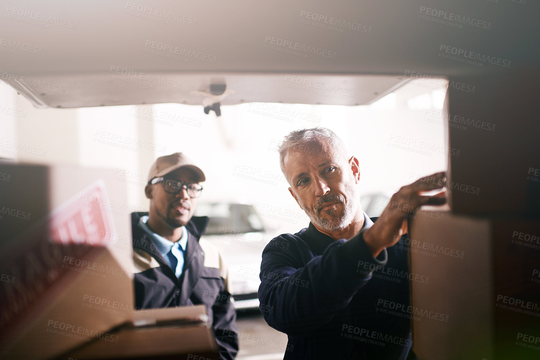 Buy stock photo Shot of delivery men loading boxes into a vehicle