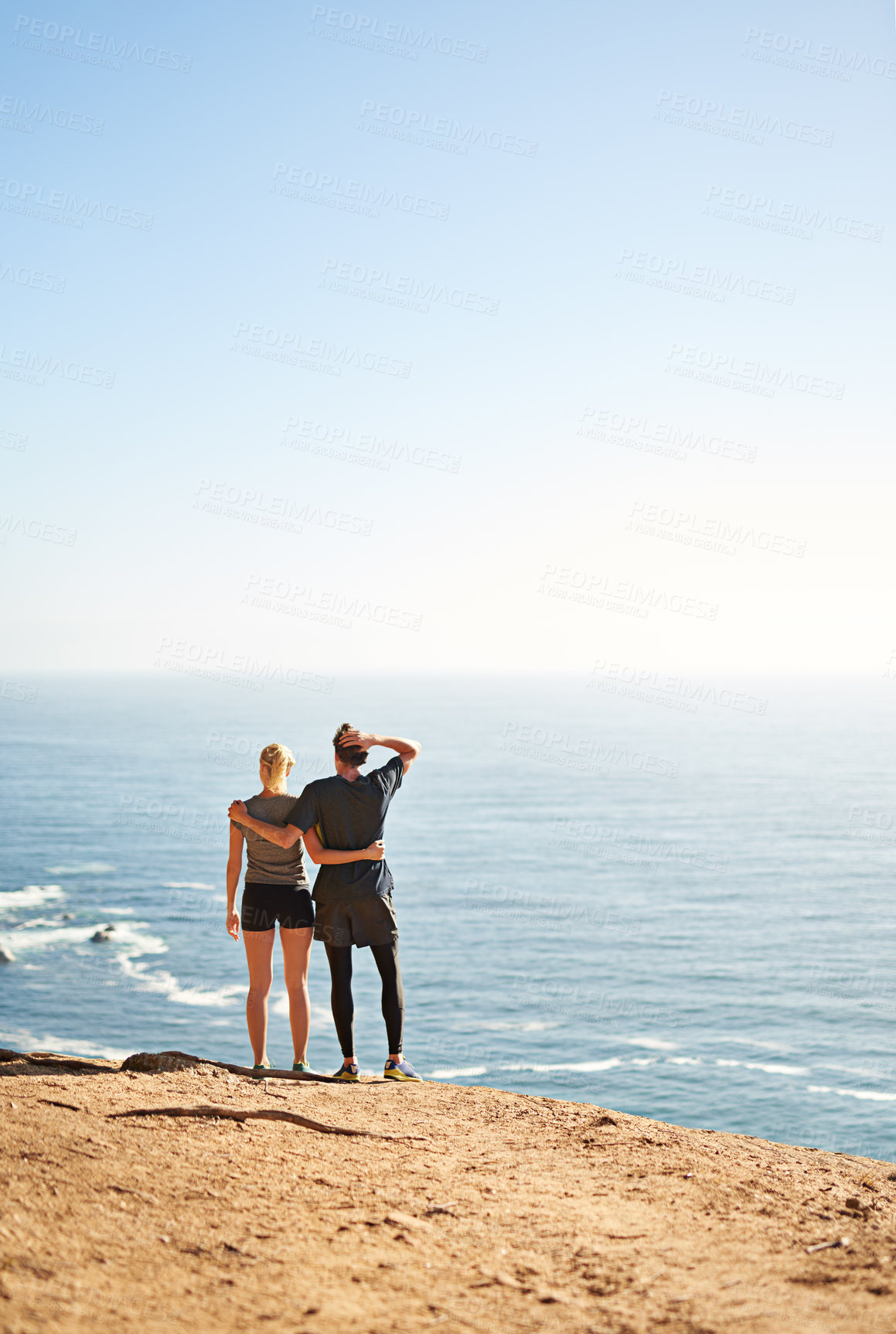 Buy stock photo Shot of a young couple looking at the view from the top of a mountain