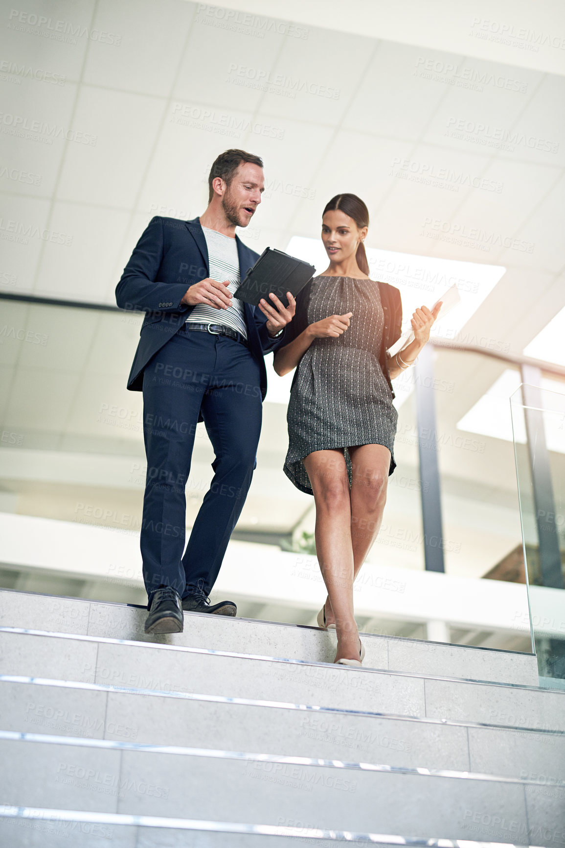 Buy stock photo Full length shot of two colleagues walking down the stairs in their office