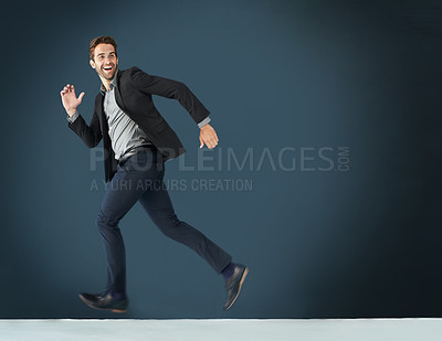 Buy stock photo Shot of a young businessman running against a dark background