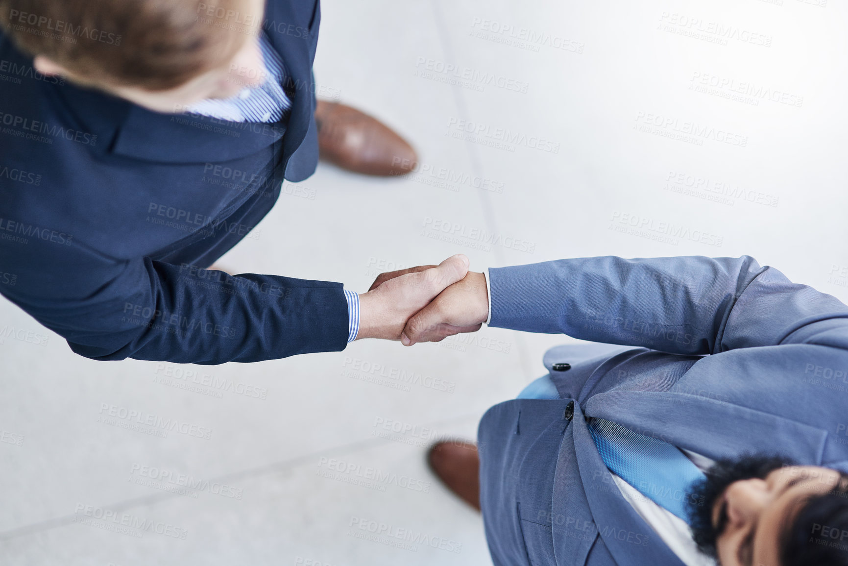 Buy stock photo High angle shot of two unrecognizable businesspeople shaking hands in a corporate office