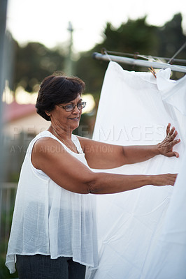 Buy stock photo Mature woman, washing line and laundry outdoor with household domestic chores, spring cleaning and housekeeping. Hanging clothes, fabric or white cotton sheet, cleaner and housework in Australia