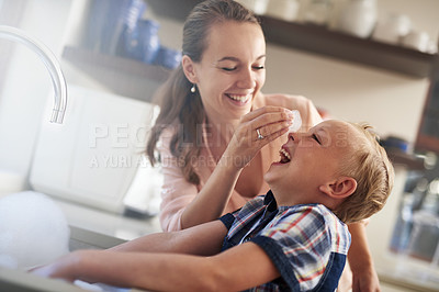 Buy stock photo Shot of a mother and son having fun while doing housework