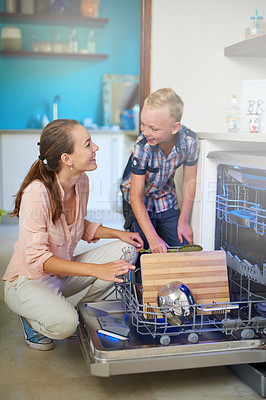 Buy stock photo Shot of a mother and son using a dishwashing machine