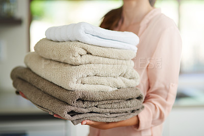 Buy stock photo Shot of a young woman carrying a pile of folded towels