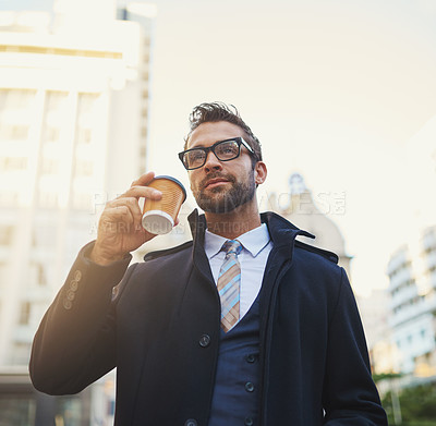 Buy stock photo Shot of a stylish man drinking a cup of coffee while out in the city