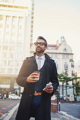 Buy stock photo Shot of a stylish man with coffee and phone in hand while out in the city