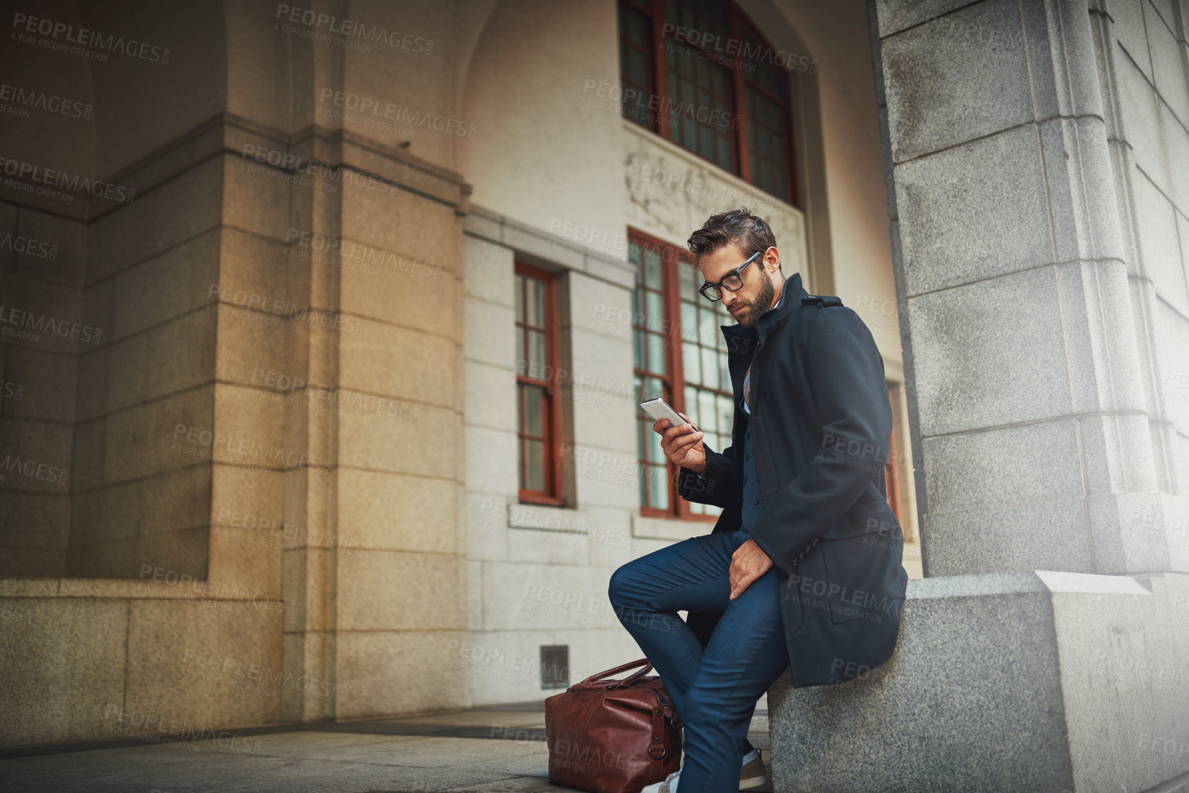 Buy stock photo Shot of a stylish man using his phone in the city