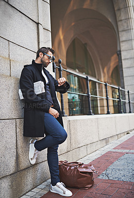 Buy stock photo Shot of a stylish young businessman checking the time while out in the city