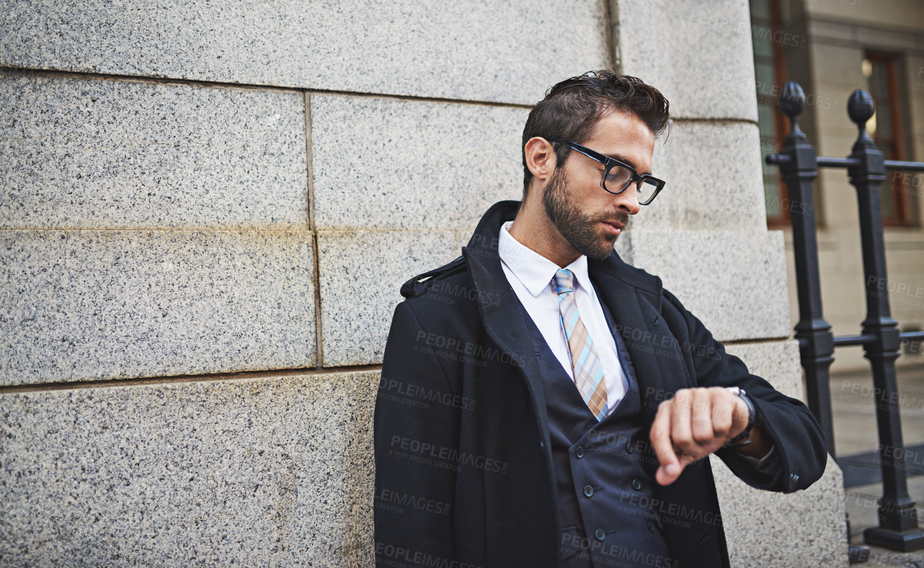 Buy stock photo Shot of a stylish young businessman checking the time while out in the city