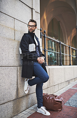Buy stock photo Shot of a stylish young man leaning against a city wall