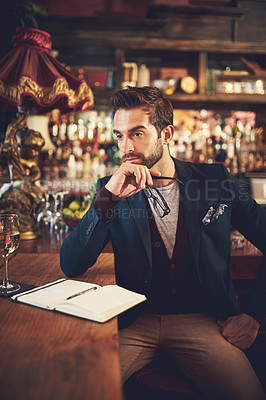 Buy stock photo Cropped shot of a young man sitting with his journal in a bar