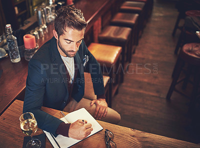 Buy stock photo High angle shot of a young man sitting with his journal in a bar