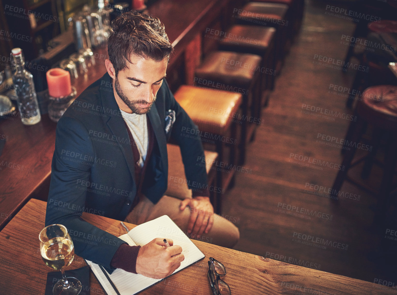 Buy stock photo High angle shot of a young man sitting with his journal in a bar
