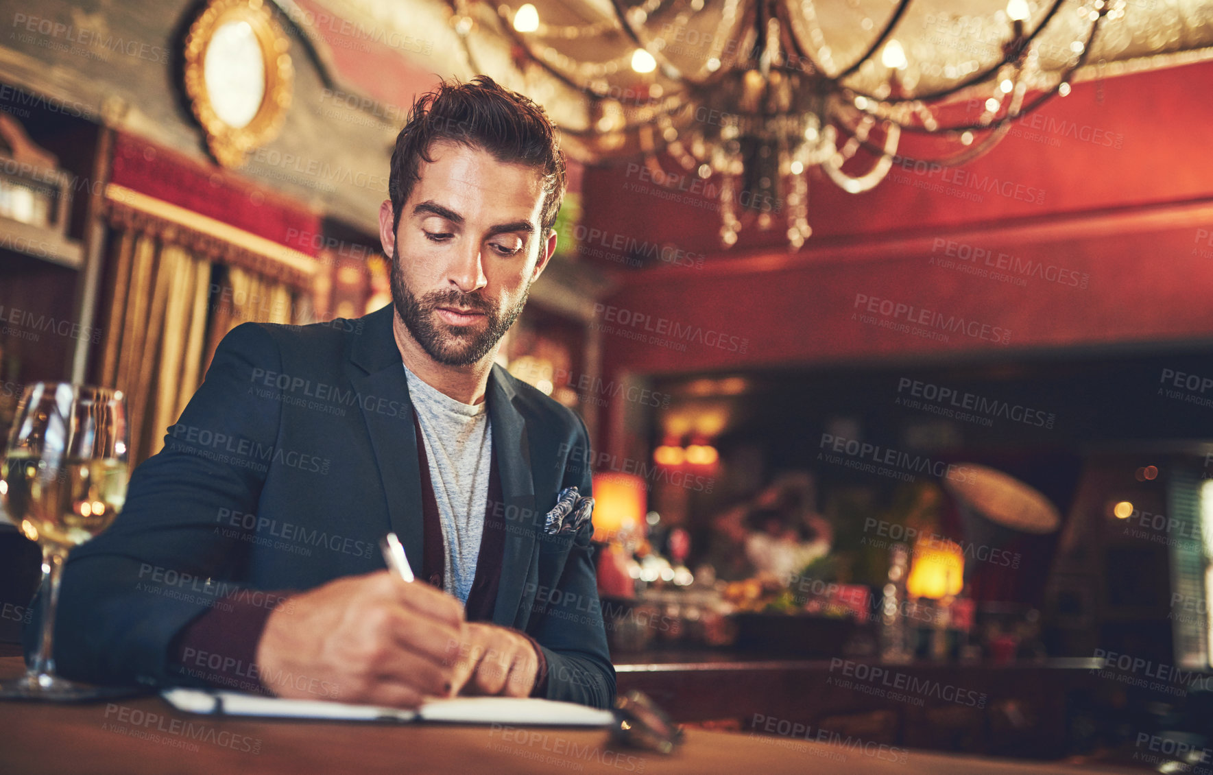 Buy stock photo Cropped shot of a young man sitting with his journal in a bar