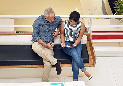 Buy stock photo Shot of a two colleagues using a digital tablet in a modern office