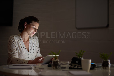 Buy stock photo Shot of a businesswoman using a digital tablet while working late in an office
