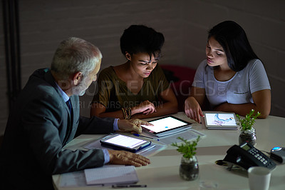 Buy stock photo Shot of a group colleagues using digital tablets while working late in an office