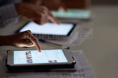 Buy stock photo Closeup shot of a group colleagues using digital tablets while working late in an office