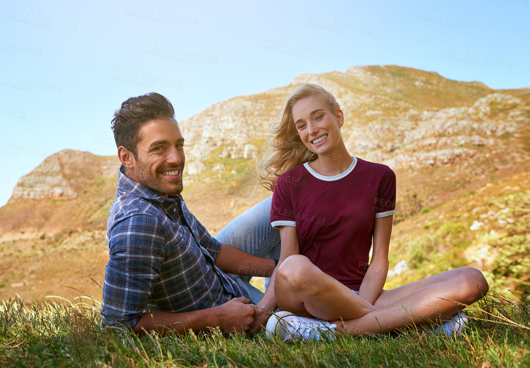 Buy stock photo Happy couple, portrait and relax with mountain on grass field for outdoor adventure, trip or holiday together in nature. Man, woman or lovers with smile on hill top for natural scenery or bonding