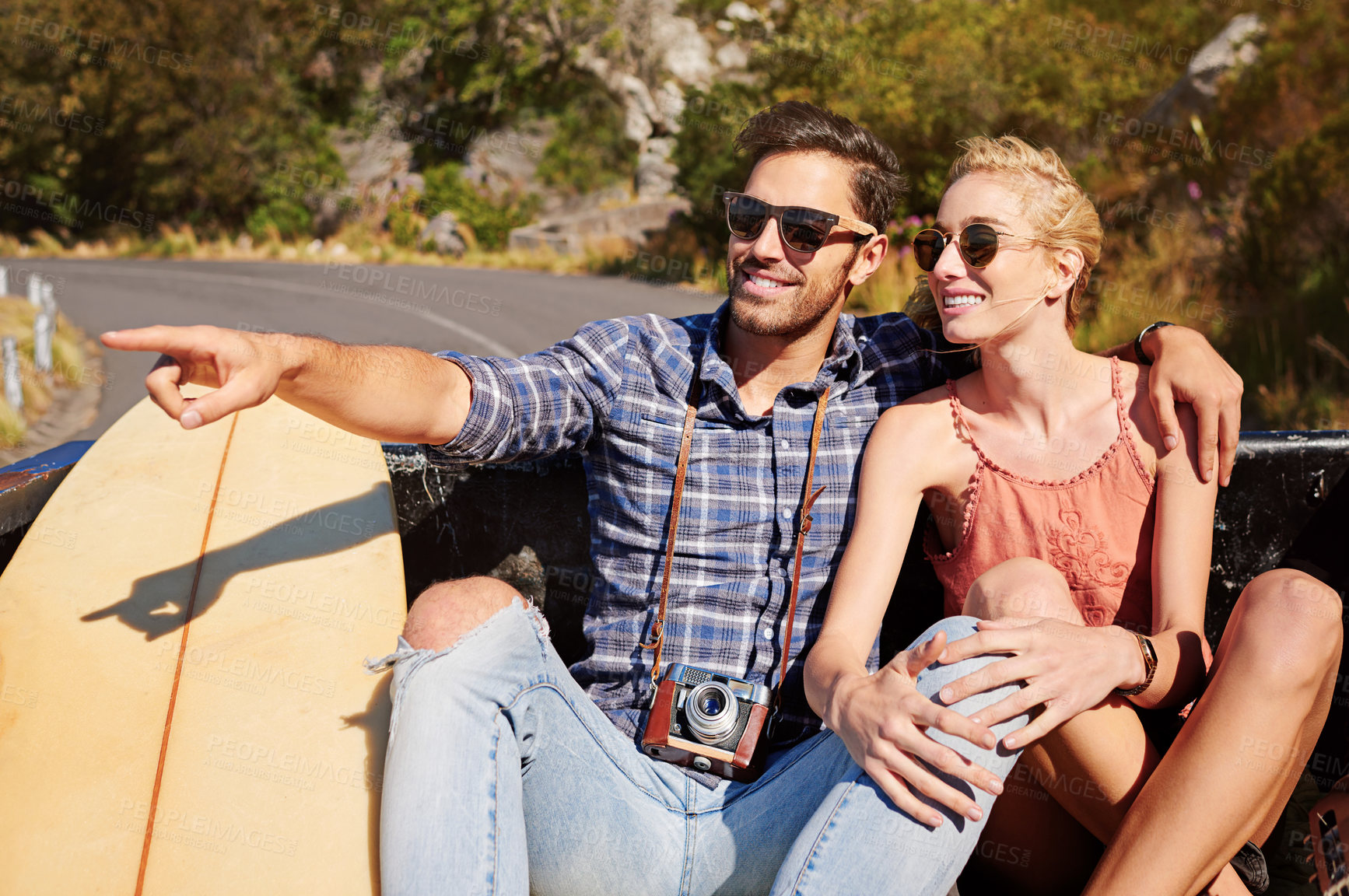 Buy stock photo Shot of a young man pointing toward something while on a road trip with his girlfriend