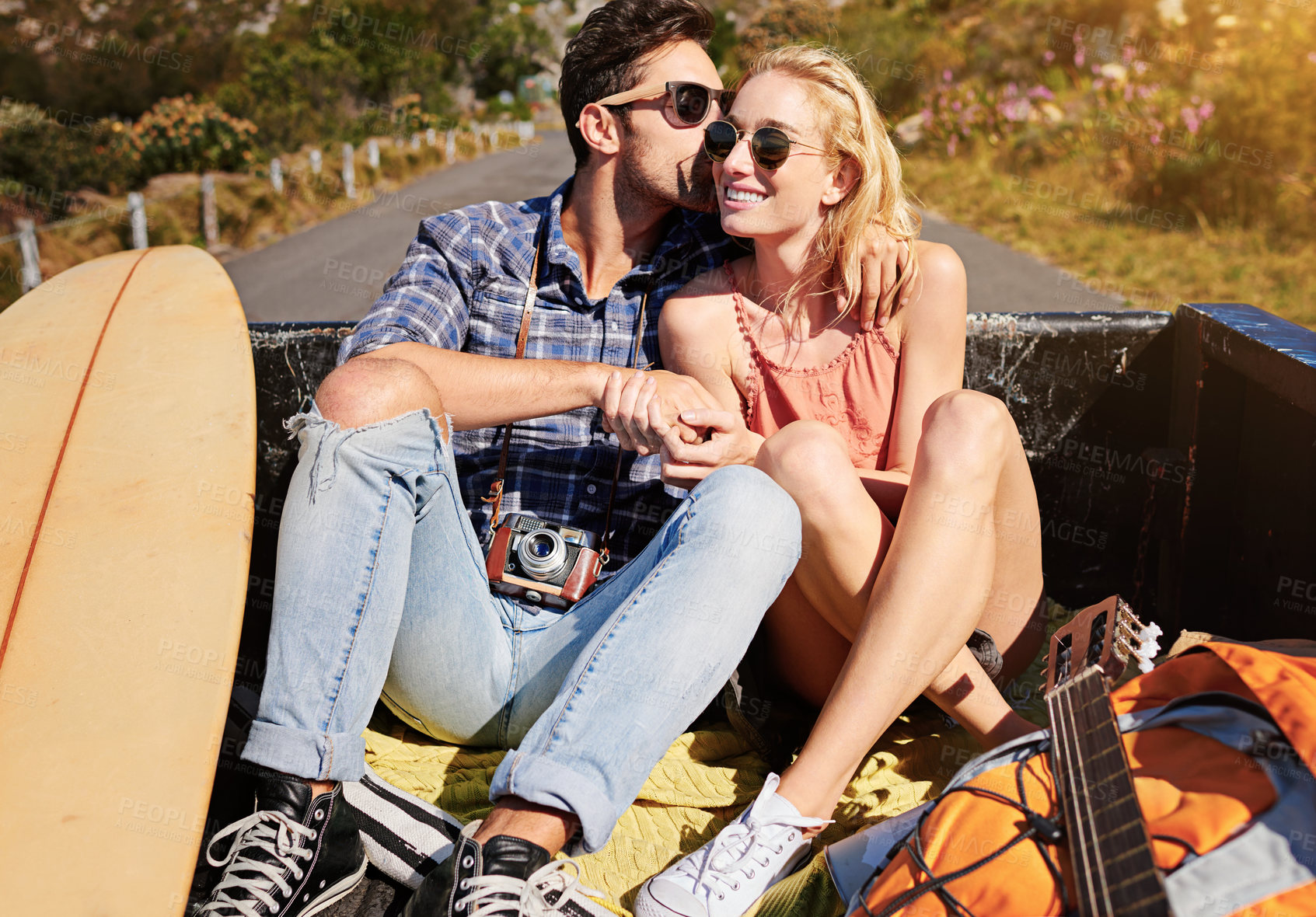 Buy stock photo Shot of a young couple relaxing on the back of a pickup truck while on a road trip