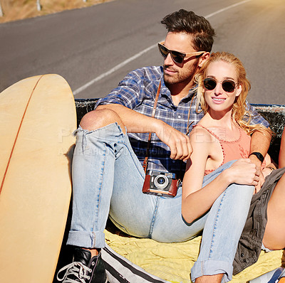 Buy stock photo Shot of a young couple relaxing on the back of a pickup truck while on a road trip