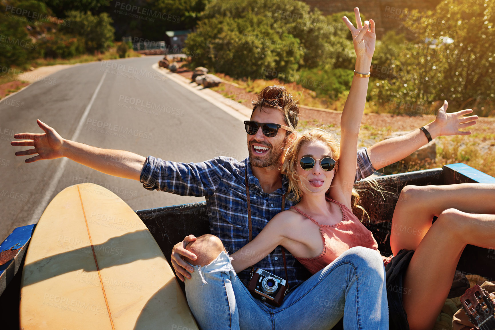 Buy stock photo Shot of a young couple relaxing on the back of a pickup truck while on a road trip