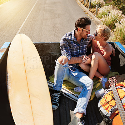 Buy stock photo Shot of a young couple relaxing on the back of a pickup truck while on a road trip