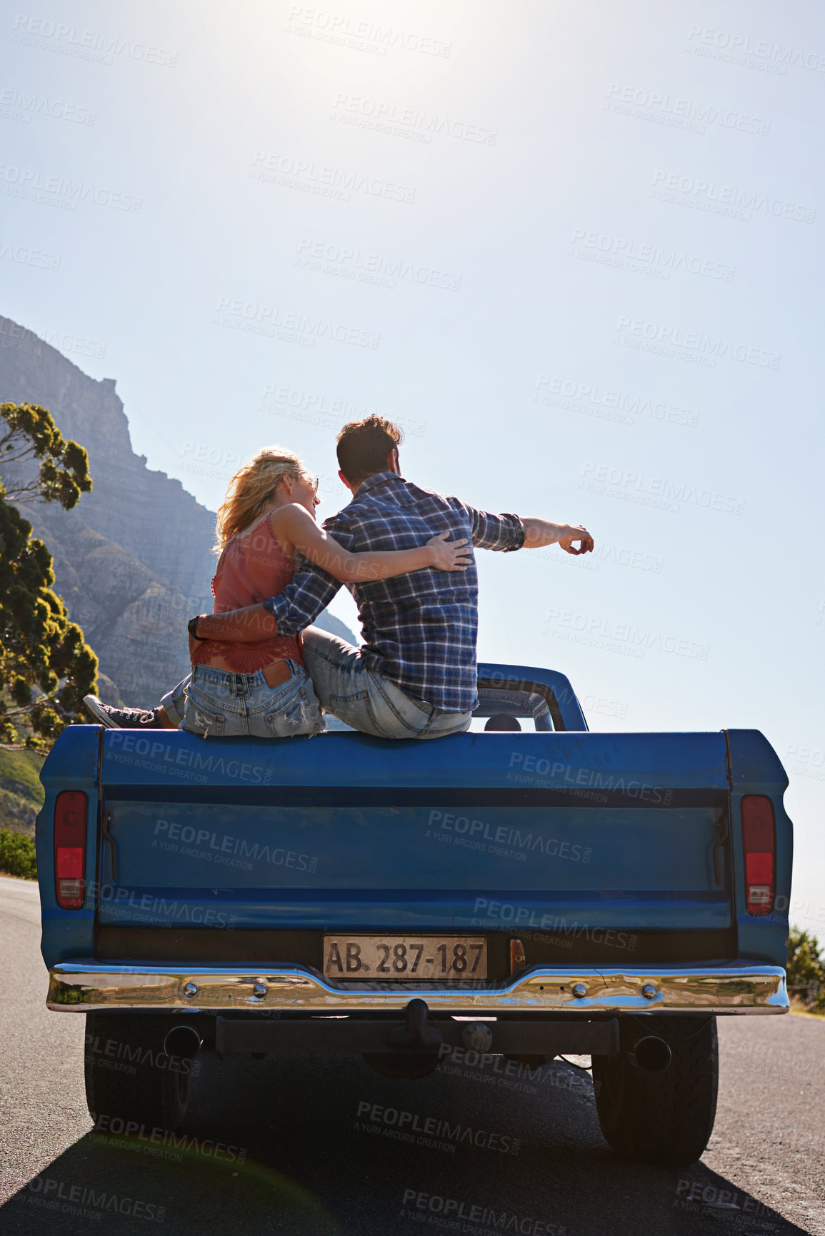 Buy stock photo Shot of a young man pointing toward something while on a road trip with his girlfriend