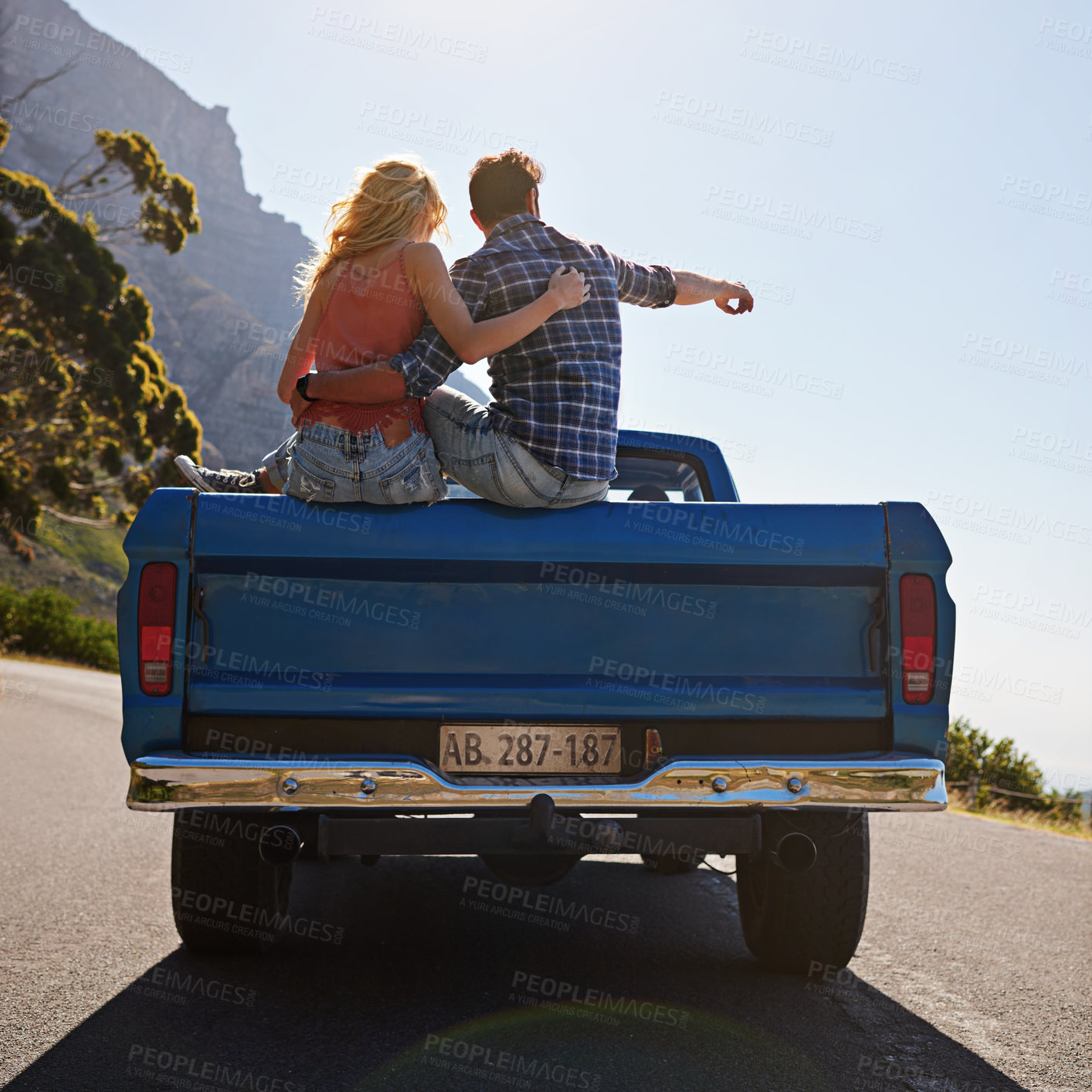 Buy stock photo Shot of a young man pointing toward something while on a road trip with his girlfriend