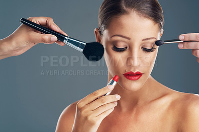 Buy stock photo Studio shot of a beautiful young woman getting her makeup done against a grey background