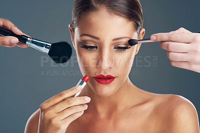 Buy stock photo Studio shot of a beautiful young woman getting her makeup done against a grey background