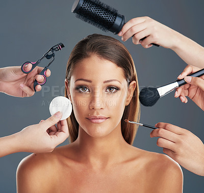 Buy stock photo Portrait shot of a beautiful young woman getting her makeup and hair done against a grey background
