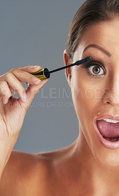 Buy stock photo Studio portrait of a beautiful young woman putting on mascara against a grey background