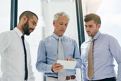 Buy stock photo Shot of a group of colleagues working on a digital tablet in an office